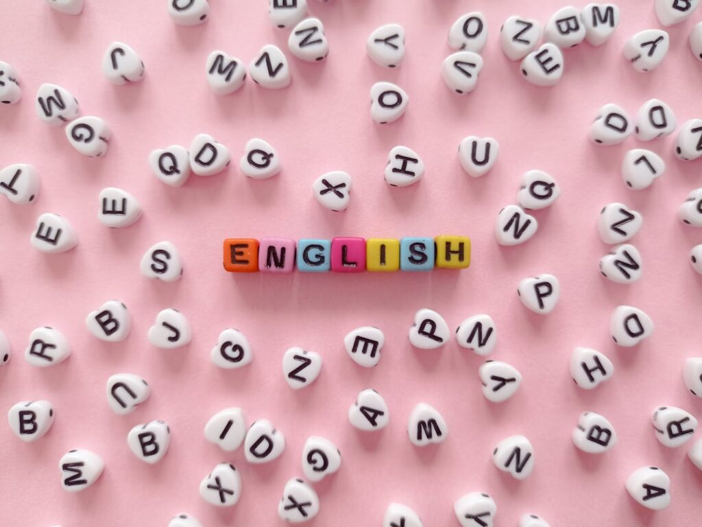 The Word English Made of Beads with Letters Lying on Pink Background